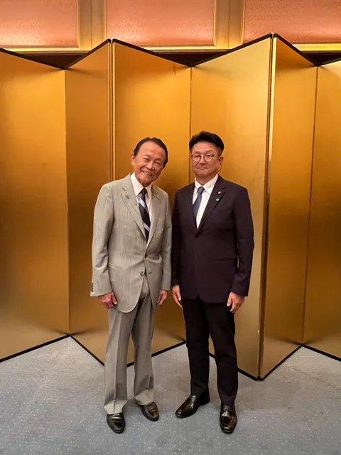 金屏風を背景に、スーツ姿の2人が並んだ記念写真