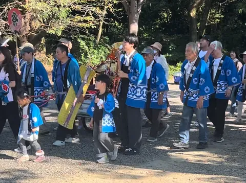 青い法被を着た大人や子どもたちが、神輿とともに歩く地域行事の様子